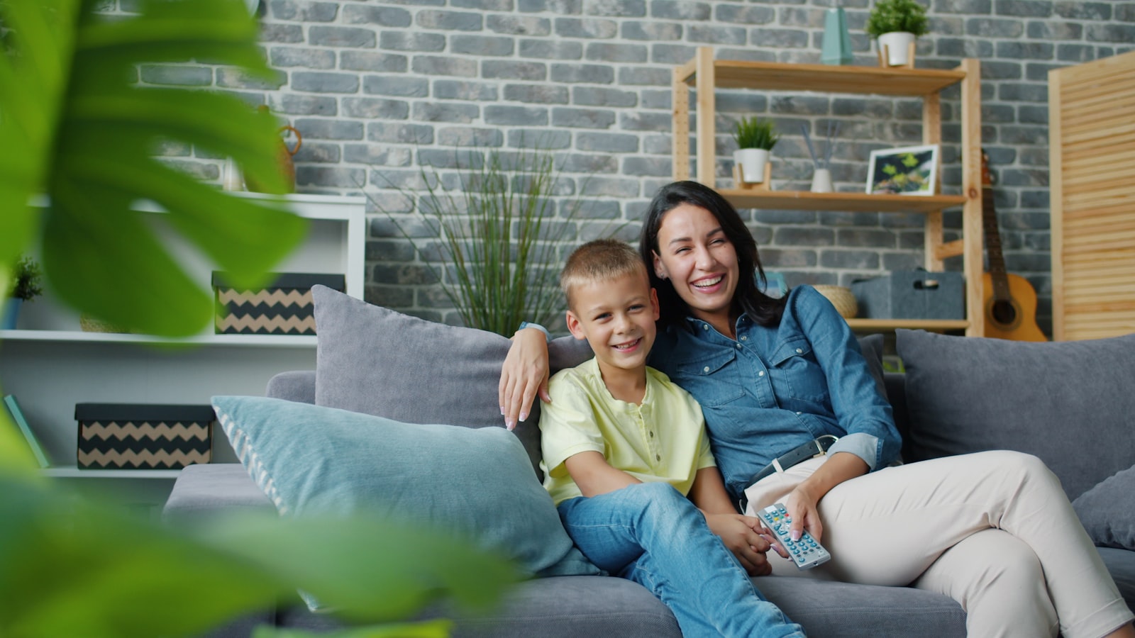 Mãe e filho sorrindo no sofá de casa